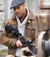 Man in a brown jacket and flat cap holding a rifle, with a blurred background